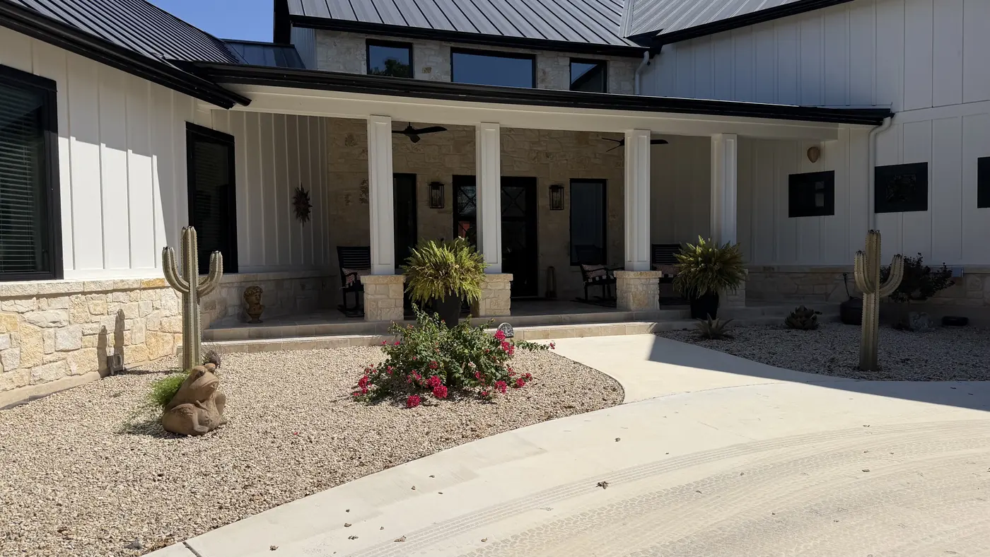 White board-and-batten home with stone-column front porch and fresh landscaping