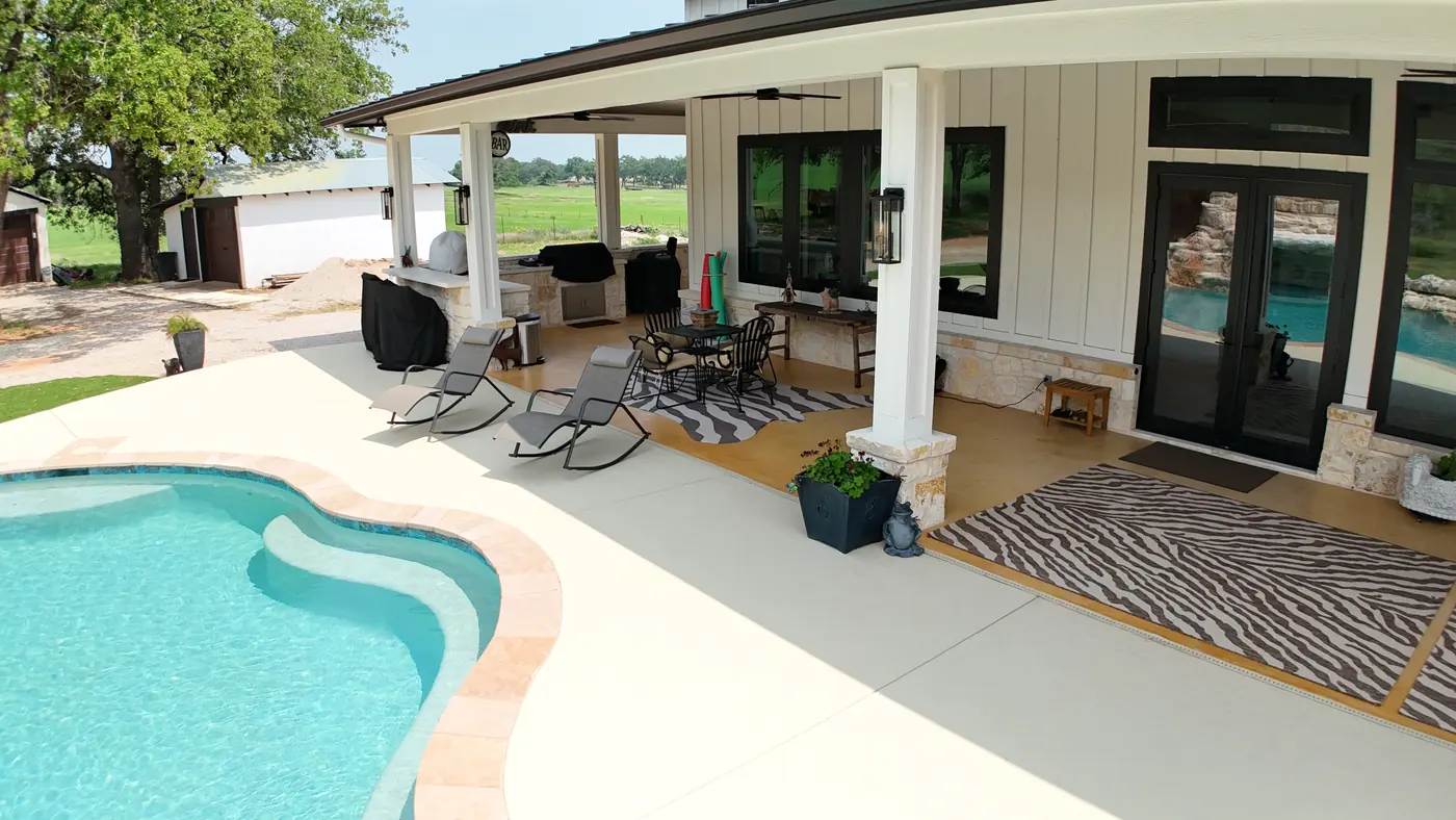 Covered patio with seating area overlooking a backyard pool