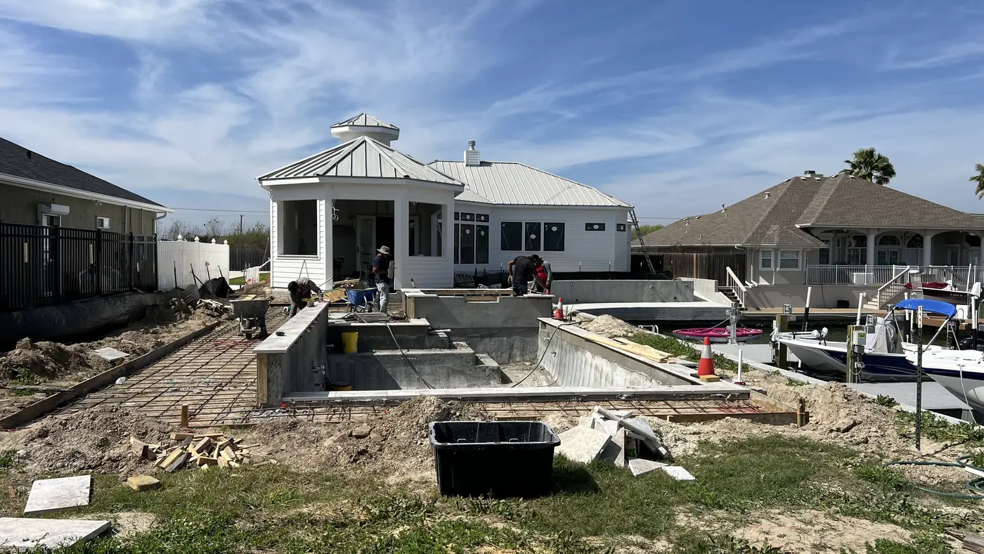 In-ground pool under construction behind a waterfront home