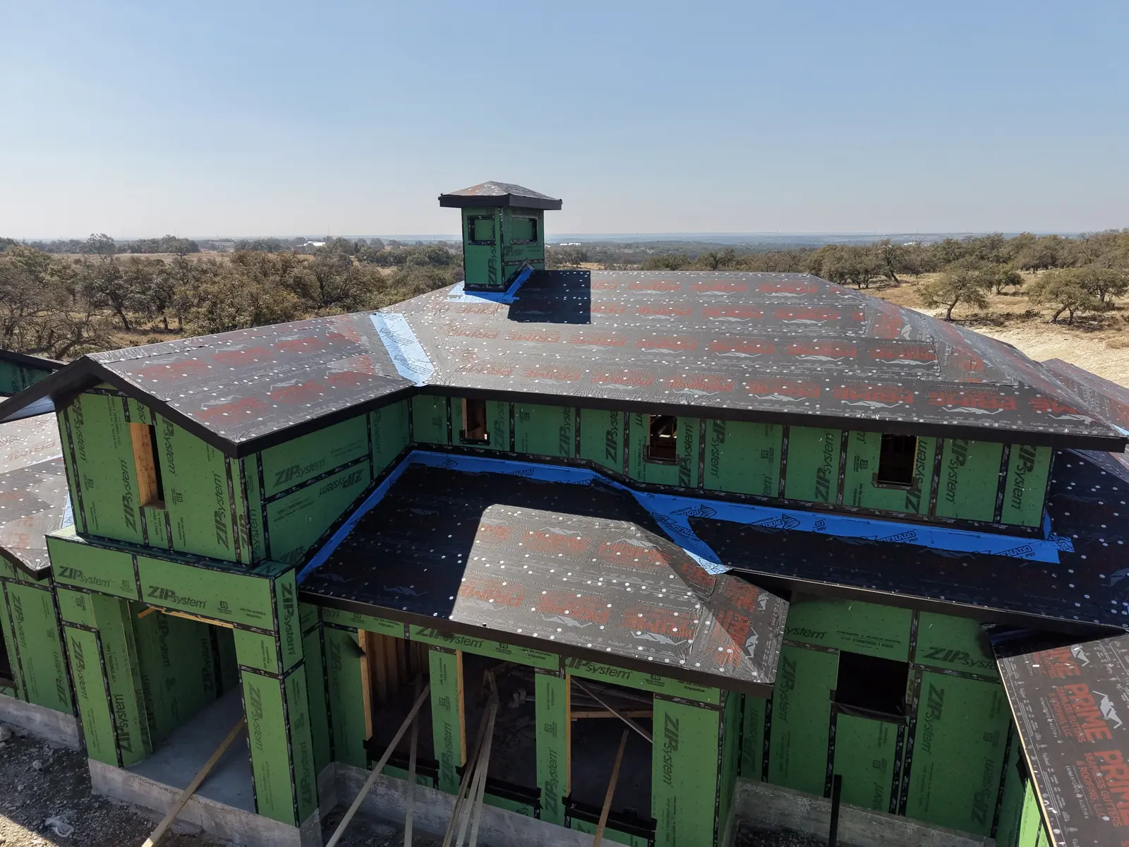 Aerial view of a custom home under construction with sheathing installed